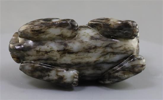 A Chinese pale grey and black jade recumbent figure of a lion-dog, length 8.3cm